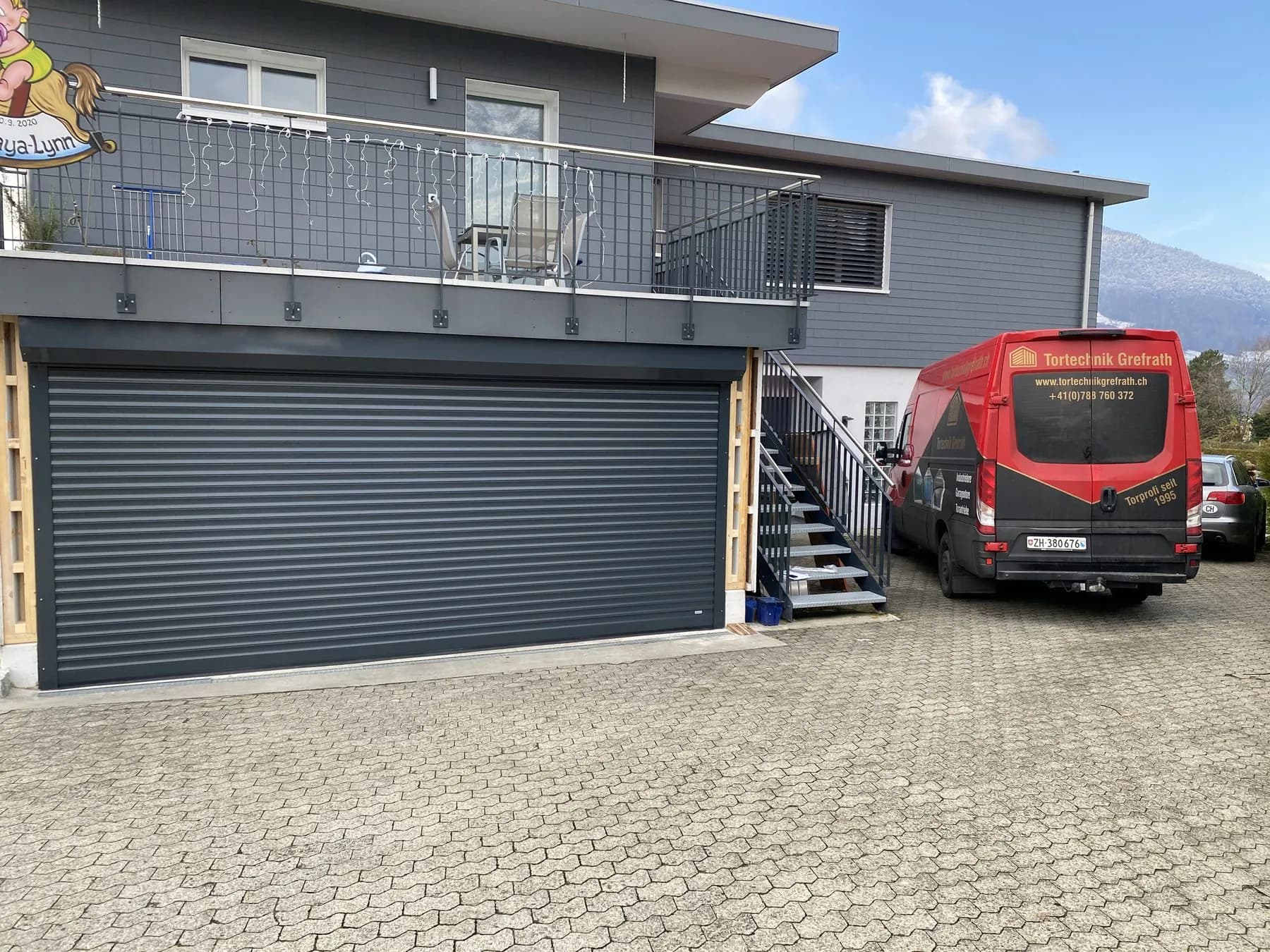 Anthrazitfarbenes Rolltor an einem Mehrfamilienhaus mit Aussentreppe