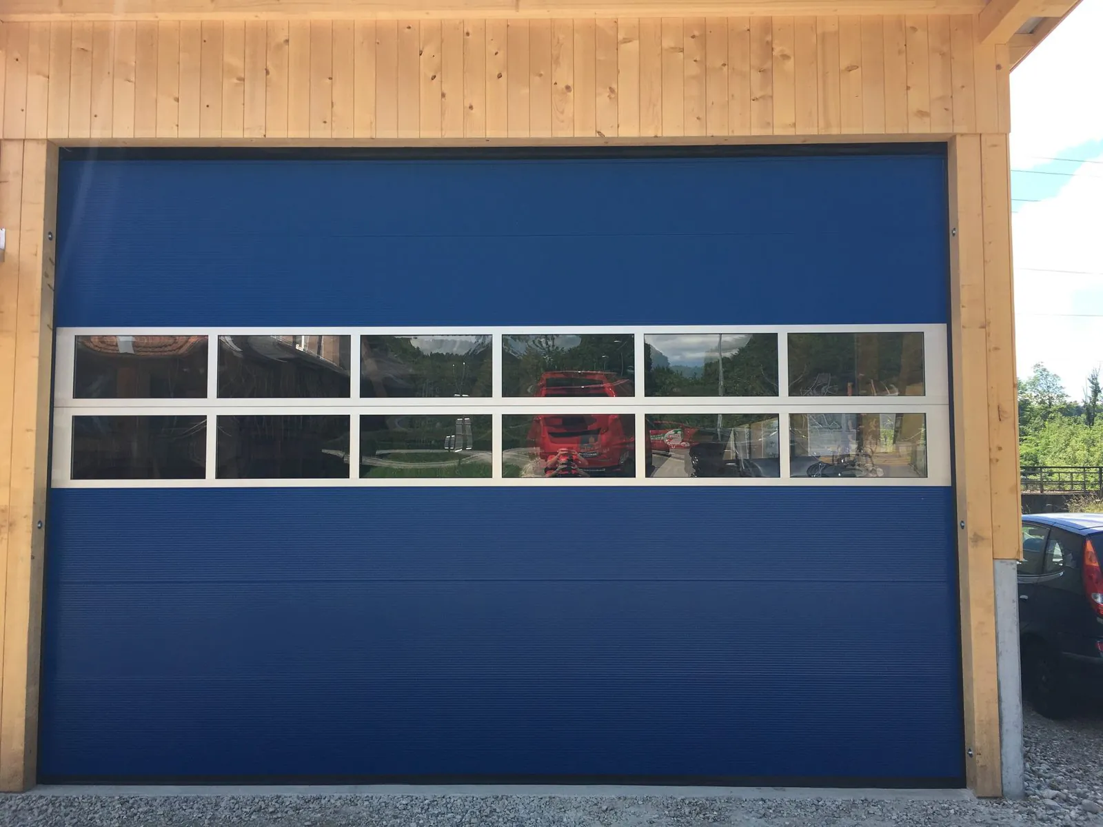 Blaues Industrietor mit Lichtband unter einer Holzkonstruktion